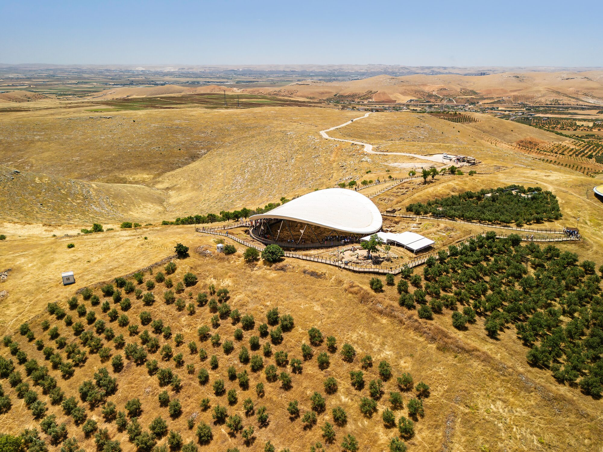Göbeklitepe from the air: the excavation shelter on its limestone ridge, orchards and fields around it